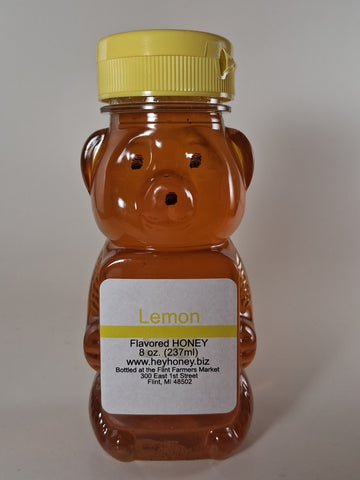 Bee-shaped lemon honey bottle with a yellow cap on a white background