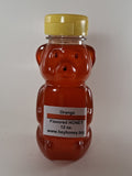 Bee-shaped bottle of orange honey with a label on a white background