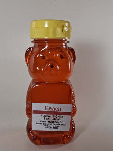 Bear-shaped honey container with peach flavor on a plain background